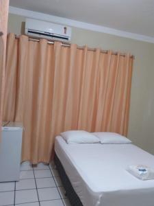 um quarto com uma cama e uma cortina laranja em Pousada Terra do Sol em Caicó