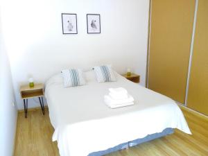 a white bed in a room with a mirror at Buenaventura Apartment in Mendoza