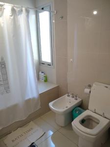 baño con aseo y lavabo y ventana en Buenaventura Apartment en Mendoza