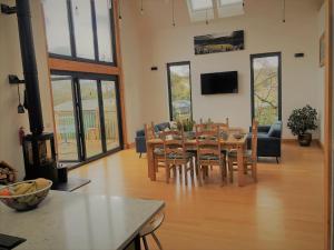 a living room with a table and chairs and a fireplace at Cranmer - New Eco Beach House 4 Bed HOT TUB & Bikes in Camber