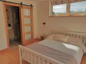 1 dormitorio con cama, ventana y espejo en Cranmer - New Eco Beach House 4 Bed HOT TUB & Bikes en Camber