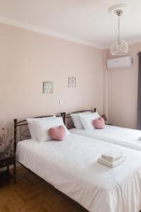 2 łóżka w pokoju z 2 różowymi poduszkami w obiekcie Sirens Athens Apartment w Atenach