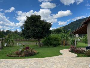 une passerelle dans un jardin avec un arbre et des fleurs dans l'établissement Chácara Bertelli, à Socorro