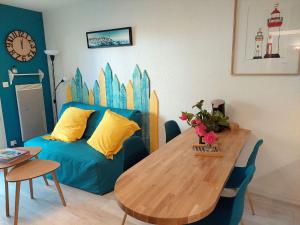 a living room with a blue couch and a wooden table at Pretty apartment with a terrace near a sandy beach in Saint-Nic