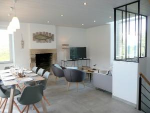 a dining room with a table and chairs and a television at Stone House in Brittany with Sea Views in Plonévez-Porzay