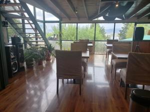 a dining room with chairs and tables and windows at Tango B&B in Ushuaia