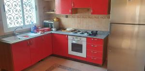 een kleine keuken met rode kasten en een koelkast bij Villa sur le golf d'Oujda avec piscine privée in Oujda