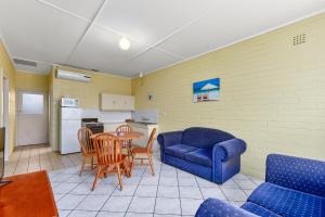 羅布的住宿－Robe Central Motel，客厅配有蓝色的沙发、桌子和椅子