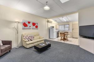 a living room with a couch and a flat screen tv at Robe Central Motel in Robe