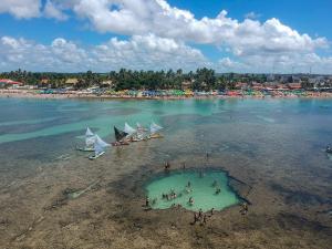 a group of people on a beach with boats in the water at PORTO DE GALINHAS MAKAMBIRA RESIDENCE in Porto De Galinhas