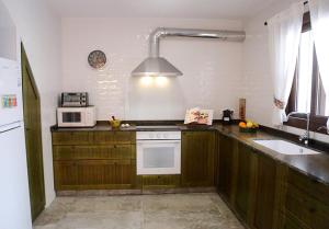 a kitchen with a stove and a sink and a microwave at Casa Sant Vicent 63 in Teulada