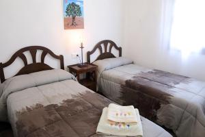 a bedroom with two beds and a table with towels at Casa Sant Vicent 63 in Teulada