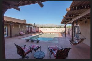 eine Terrasse mit einem Pool, Stühlen und einem Tisch in der Unterkunft Turtle Back Mesa Bed and Breakfast in Indio