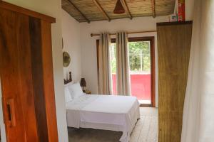 1 dormitorio con cama blanca y ventana en Casas e apartamentos da Ilda, en Trancoso