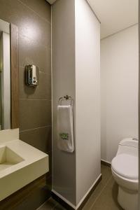 a bathroom with a toilet and a white towel at Lleras Green Hotel in Medellín
