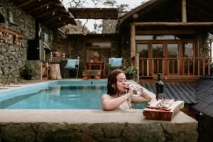 a woman drinking from a bottle of water next to a swimming pool at AYAR - Portentos & Cabañas QHAPAQ in Virú