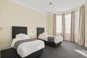 ein Hotelzimmer mit 2 Betten und Fenstern in der Unterkunft House on Grosvenor in Sandy Bay