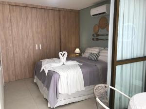 ein Schlafzimmer mit einem Bett mit zwei Schwänen darauf in der Unterkunft Flat aconchegante no Eco Resort Praia dos Carneiros - Cama Queen in Tamandaré