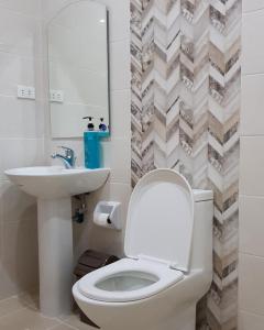 a bathroom with a toilet and a sink and a mirror at Acrige Apartelle 2 pax Twin @ heart of Bogo City in Banban