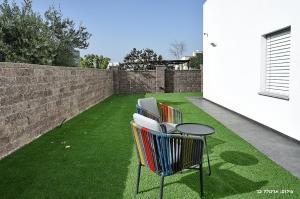 two chairs and a table on a lawn at סוויטה חדשה ויפהיפיה in Hagoshrim