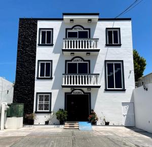 ein weißes Apartmenthaus mit einer schwarzen Tür in der Unterkunft Hotel Santa Isabel in Ciudad del Carmen