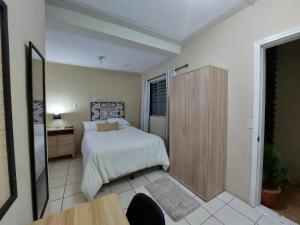 a bedroom with a bed and a wooden cabinet at Habitación Privada en RESIDENCIAL Villa de Las Hadas in Tegucigalpa