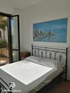 a bed in a bedroom with a painting on the wall at casetta in centro paese a 2 passi dalla piazza Matrice in Favignana