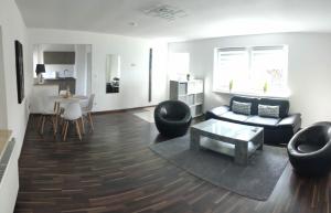 un soggiorno con un divano, sedie e un tavolo di Ferienhaus Dobberzin nahe Mündesee ad Angermünde Altre 3 foto