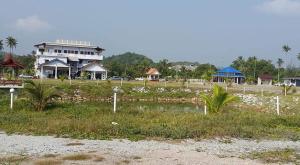 a building in a field with a pond in front at Dlavender Beach Stay in Marang