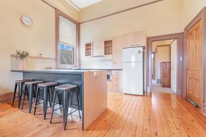 a kitchen with a counter with stools and a refrigerator at Clocktower Suites in Echuca