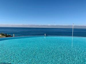 a large blue swimming pool next to the ocean at Beachfront Condo close Puerto Nuevo, Papas, and Valle de Guadalupe in Rosarito