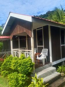 una casa con una silla blanca en el porche en Juara Cottage, en Tioman Island 6 fotos más