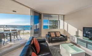a living room with a couch and a tv and a table at Sandcastle Apartments in Port Macquarie