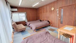 松江市にあるゲストハウス あずも GuestHouse AZMOのベッド2台、椅子、テーブルが備わる客室です。