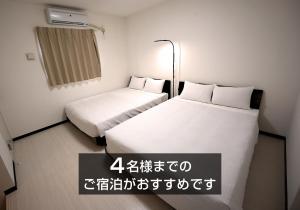two beds in a small room with writing on the wall at KARCHIBE ISHIGAKI in Ishigaki Island