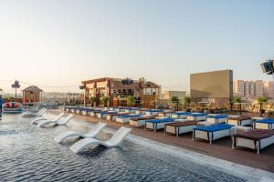 una piscina en un complejo con sillas y mesas en Avani Ibn Battuta Dubai Hotel, en Dubái