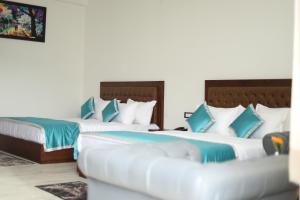 two beds in a hotel room with blue pillows at Chakrata Inn Resort in Chakrāta