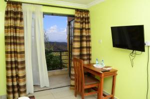 Habitación con mesa, TV y ventana. en ACK Resort Salama en Salama