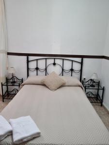 1 dormitorio con 1 cama blanca grande y 2 almohadas en Pensión Javier, en Sevilla