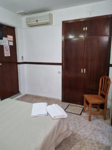 sypialnia z łóżkiem, drewnianą szafką i krzesłem w obiekcie Pensión Javier w Sewilli