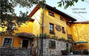 a yellow building with a stone wall at Casa Rural Los campos in Corao