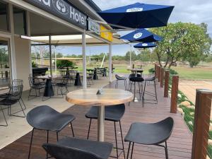 patio ze stołami, krzesłami i parasolami w obiekcie Banana Hotel Motel w mieście Banana