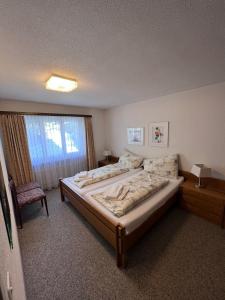 ein Schlafzimmer mit einem Bett, einem Stuhl und einem Fenster in der Unterkunft Valère Apartments in Leukerbad