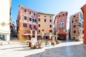 eine Stadtstraße mit Gebäuden, Tischen und Sonnenschirmen in der Unterkunft BELLA CAMPAGNA - Luxury Two Bedroom Apartment in Rovinj