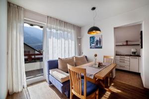 een woonkamer met een tafel en een blauwe bank bij Schnitzer Ferienwohnung Enzian in Rablà