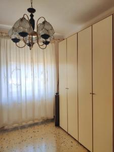 Cette chambre est dotée de rideaux blancs et d'un lustre. dans l'établissement Appartamento ultra comodo -Torino, à Turin