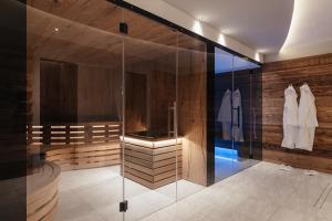 y baño con ducha de cristal y paredes de madera. en Garnì La Dorada, en Colfosco