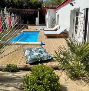 a wooden deck with a swimming pool in a backyard at Villa avec Piscine à 5 minutes de l’océan in Bidart