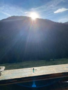 a sun shining over a field with a wooden bench at Almhütte Prem2 in Ramingstein