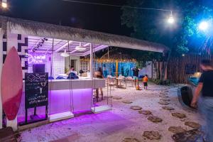 a surf shop with purple lights in the sand at night at Peggy's Cove Resort in Chao Lao Beach +214 photos